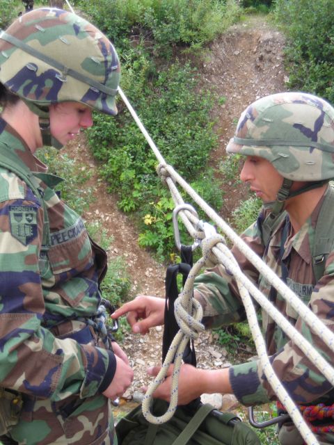 2003 Jeep TJ - Two soldiers in camouflage uniforms and helmets are shown practicing rappelling techniques with ropes and carabiners.