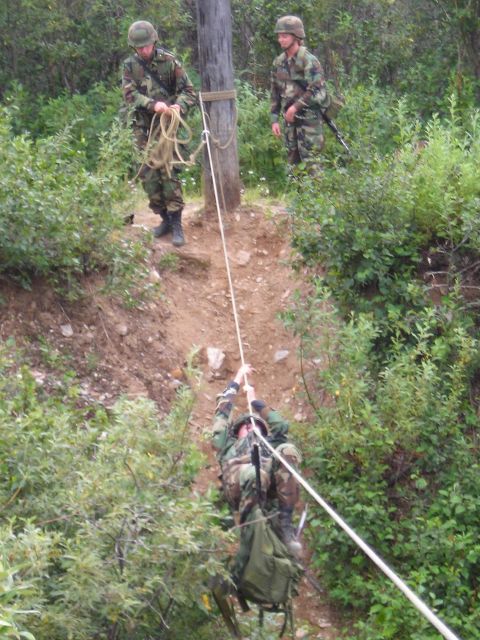 2003 Jeep TJ - Soldiers practice rappelling down a steep, wooded incline using ropes and a central pole for support.