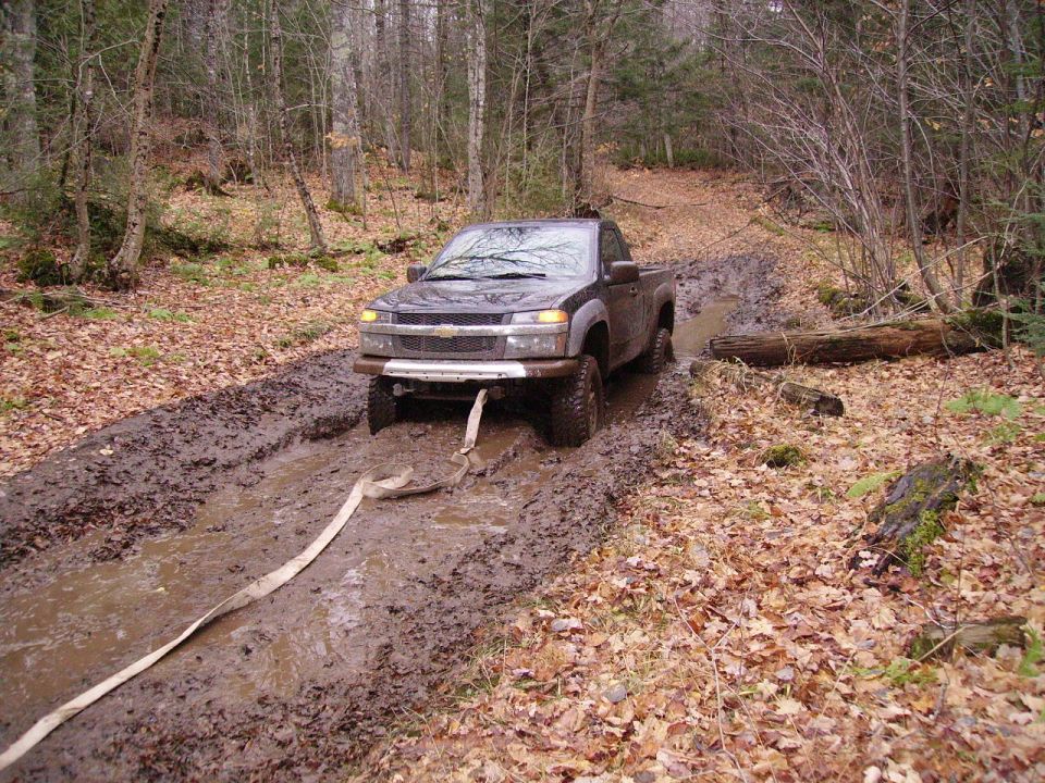 Chevrolet Colorado truck stuck in mud on a wooded trail, front view