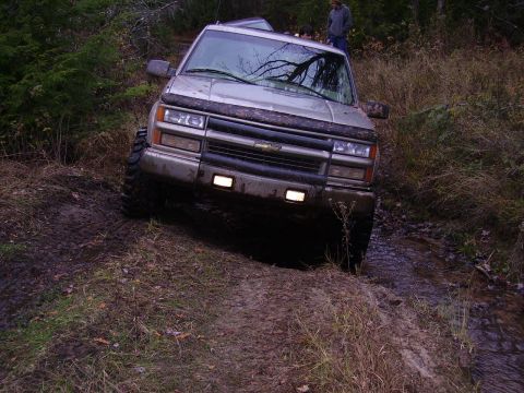 2000 Chevrolet Tahoe - A silver Chevrolet Tahoe navigates a challenging muddy terrain with its front end angled towards the viewer.