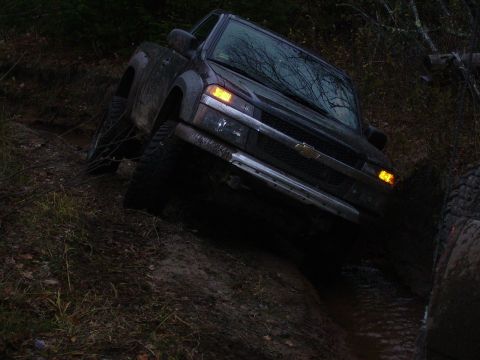 2000 Chevrolet Tahoe - A dark pickup truck navigates a challenging muddy terrain with its front wheels angled.