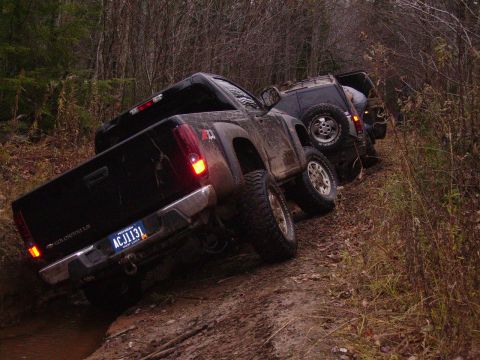 2000 Chevrolet Tahoe - Two off-road vehicles are stuck in the mud on a wooded trail.