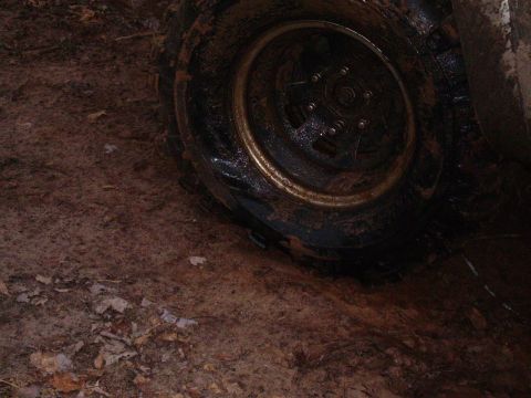 2000 Chevrolet Tahoe - Close-up of a muddy tire and wheel sunk into the dirt.