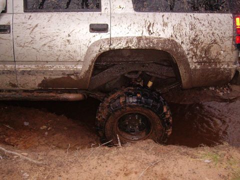 2000 Chevrolet Tahoe - This vehicle is heavily covered in mud and appears to be stuck in a muddy terrain.