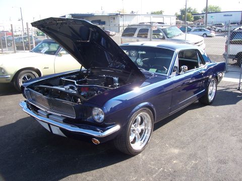2002 Ford Mustang - A classic dark blue Ford Mustang from the mid-1960s is displayed with its hood open, revealing the engine compartment.