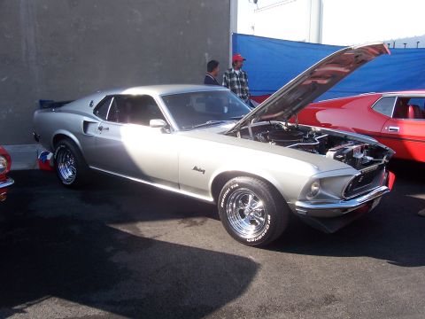 2002 Ford Mustang - A silver 1969 Ford Mustang is displayed with its hood open, parked next to a red car.