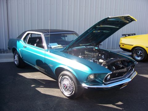 2002 Ford Mustang - This teal 1969 Ford Mustang coupe features a black vinyl roof and wire wheels, with its hood open to display the engine.