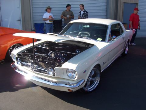 2002 Ford Mustang - A classic white 1965 Ford Mustang coupe is displayed with its hood open, revealing the engine bay.