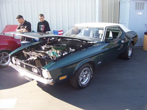 2002 Ford Mustang - A green classic Mustang with its hood up is displayed outdoors, with two people observing the engine.
