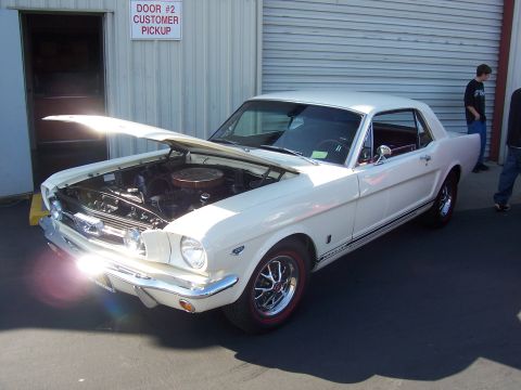 2002 Ford Mustang - Classic white Ford Mustang coupe with hood open, parked outside a building.