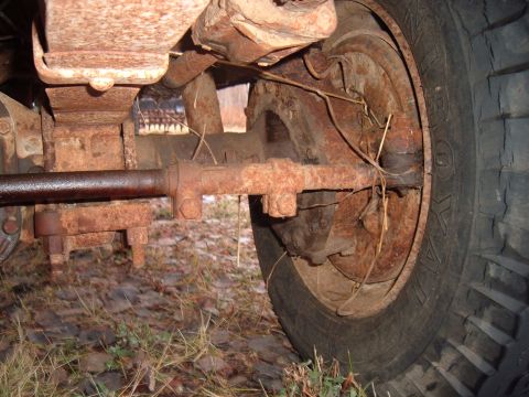 1979 Ford Bronco - Close-up view of the heavily rusted undercarriage and tire of an unidentified vehicle.