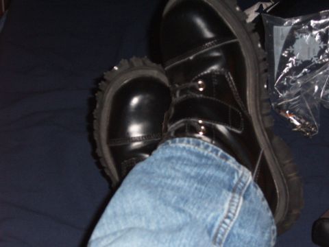 1993 Ford Bronco - A pair of shiny black combat boots with thick soles and metal eyelets are shown with blue jeans.