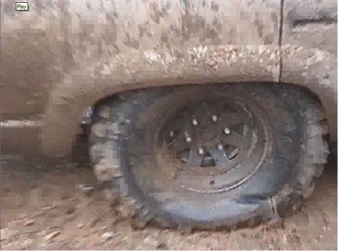 2000 Chevrolet Tahoe - A vehicle's tire is submerged in mud, with the fender covered in dirt.