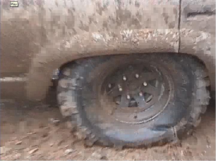 Muddy tire and fender of a vehicle stuck in the dirt