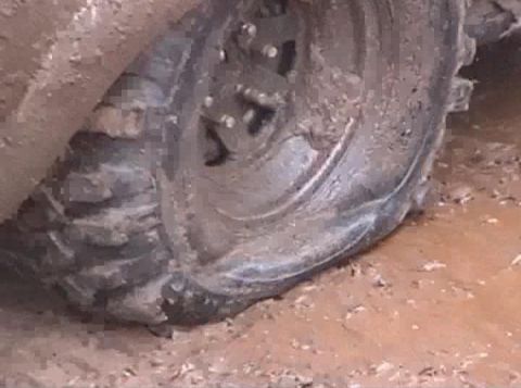 2000 Chevrolet Tahoe - Close-up of a muddy tire and wheel stuck in the mud.