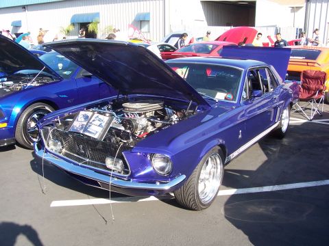 2002 Ford Mustang - A classic 1968 Ford Mustang GT is displayed with its hood open, alongside a newer model Mustang.