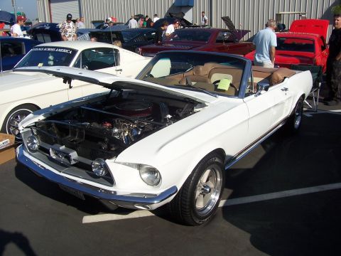 2002 Ford Mustang - White 1967-1968 Ford Mustang convertible displayed with hood open at an outdoor car show.