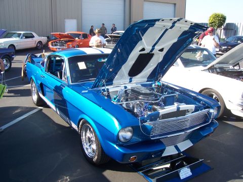 2002 Ford Mustang - A classic blue Ford Mustang with its hood open, displayed at an outdoor event with other vehicles.