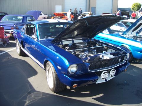 2002 Ford Mustang - A classic blue Mustang is displayed with its hood up, revealing the engine bay. Other vehicles are visible in the background.