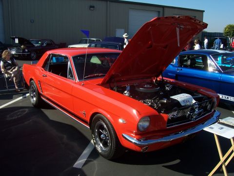 2002 Ford Mustang - A red 1965 Ford Mustang is displayed with its hood open at an outdoor car show.