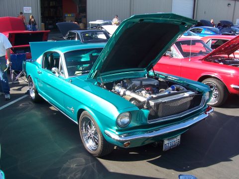 2002 Ford Mustang - A teal 1965 Ford Mustang is displayed with its hood open, revealing a modified engine and custom grille.