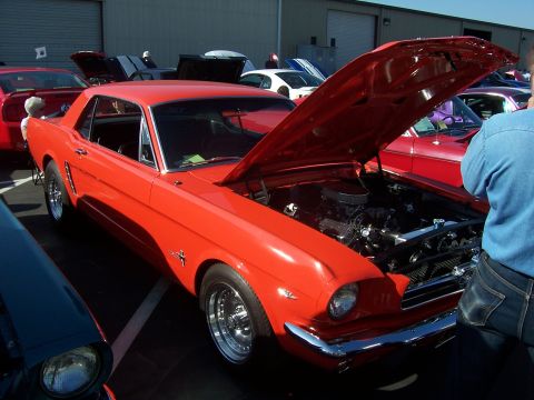 2002 Ford Mustang - This classic red Mustang coupe, likely a 1965 model, is displayed with its hood open, revealing the engine bay.
