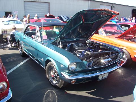 2002 Ford Mustang - A teal 1965 Ford Mustang coupe is displayed with its hood open at an outdoor car show.
