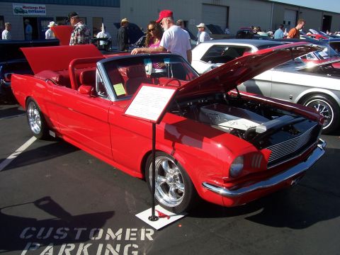 2002 Ford Mustang - This red 1965 Ford Mustang convertible is on display with its hood open, revealing the engine bay.
