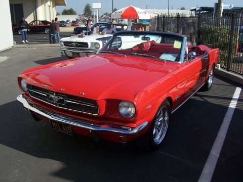 2002 Ford Mustang - A red convertible classic car is parked next to a white classic car.