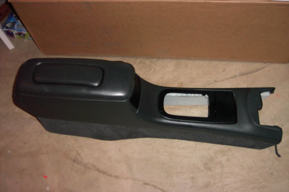 Black center console with armrest and shifter cutout on shop floor