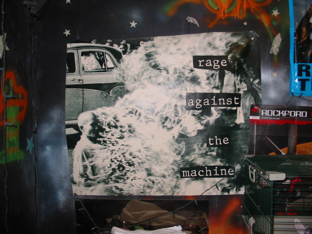 Poster of a man engulfed in flames next to a vintage car, with "Rage Against The Machine" text