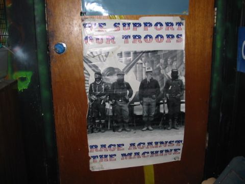 1997 Ford Crown Victoria - Poster with armed men and political slogans is taped to a wooden door.