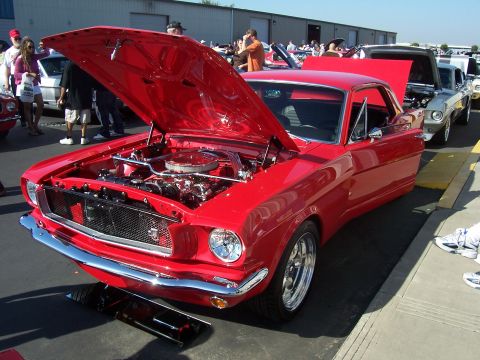 2002 Ford Mustang - A classic red Ford Mustang is displayed with its hood open at a car show event.