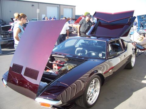 2002 Ford Mustang - A De Tomaso Pantera is displayed with its hood and engine compartment open, attracting attention at an outdoor event.