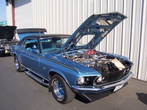 2002 Ford Mustang - Classic blue Ford Mustang with its hood open, parked next to another vehicle.