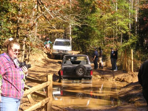 1996 Ford Bronco - Off-roading adventure with multiple vehicles on a muddy path in the woods.