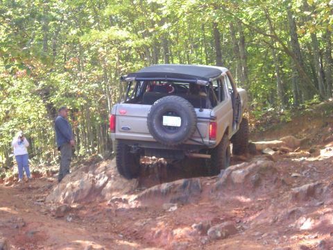 1996 Ford Bronco - A Ford Bronco navigates a steep, rocky trail surrounded by trees.