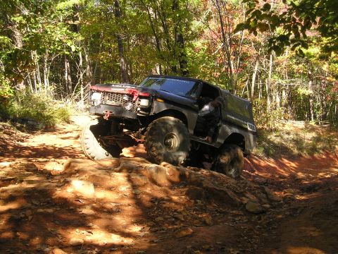 1996 Ford Bronco - Modified Ford Bronco navigating a challenging rocky trail in a wooded area.