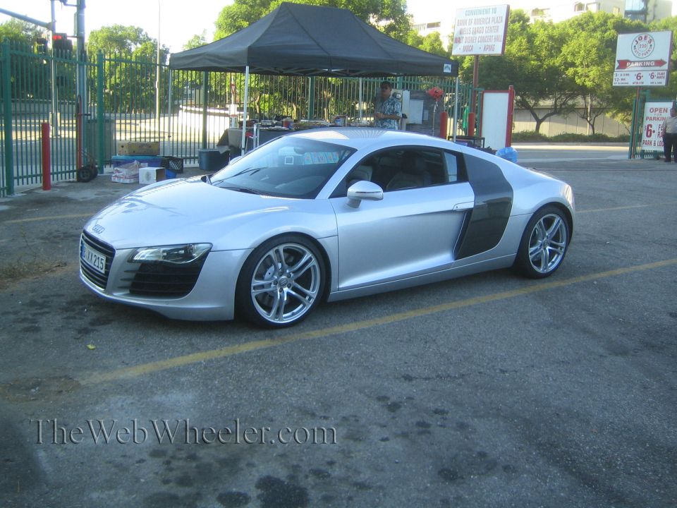 Silver Audi R8 parked on asphalt with yellow lines. Black side blade detail visible