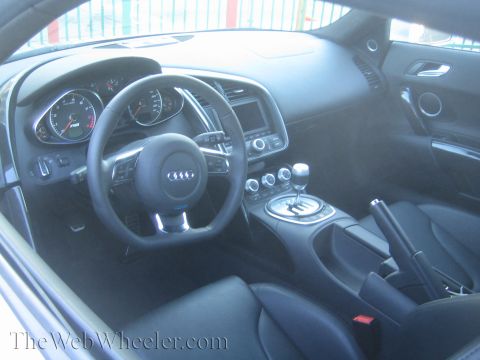 1968 Ford Mustang - The interior of an Audi R8 showcases its modern dashboard, steering wheel, and gear shifter.