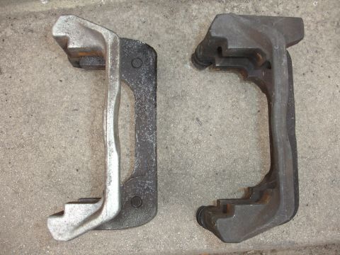 1993 Ford Taurus - Comparison of two brake caliper brackets, one appearing newer than the other.
