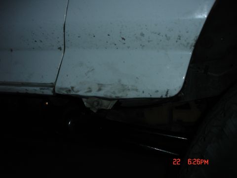 1996 Ford Bronco - The underside of a vehicle shows wear and tear on the lower body panel and frame.