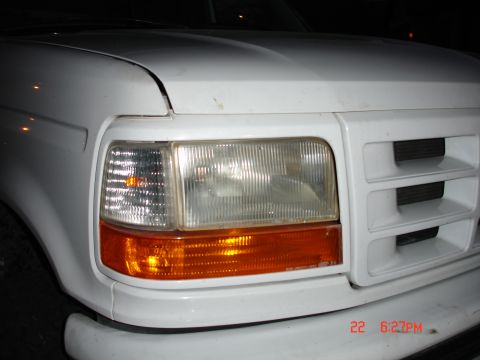 1996 Ford Bronco - Close-up of a white Ford truck's front corner, showing the headlight and grille details.