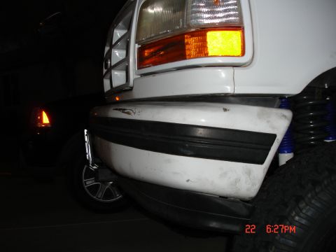 1996 Ford Bronco - Front view of a white SUV's bumper and headlight, with another vehicle in the background.