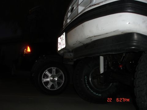 1996 Ford Bronco - Two vehicles are parked close together at night, one white SUV and one black car.