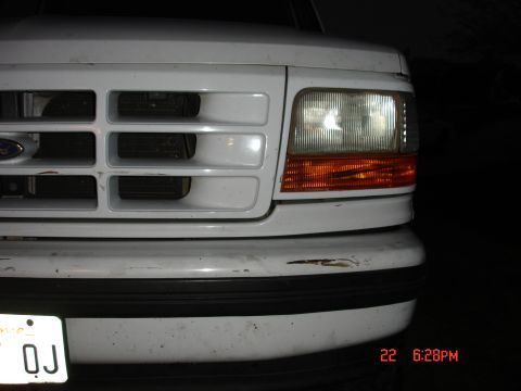 1996 Ford Bronco - Close-up of the front grille and headlight on a 1996 Ford Bronco. The license plate is visible.