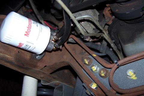 1990 Ford Bronco - Close-up of a Motorcraft oil filter and associated plumbing on a vehicle's undercarriage.
