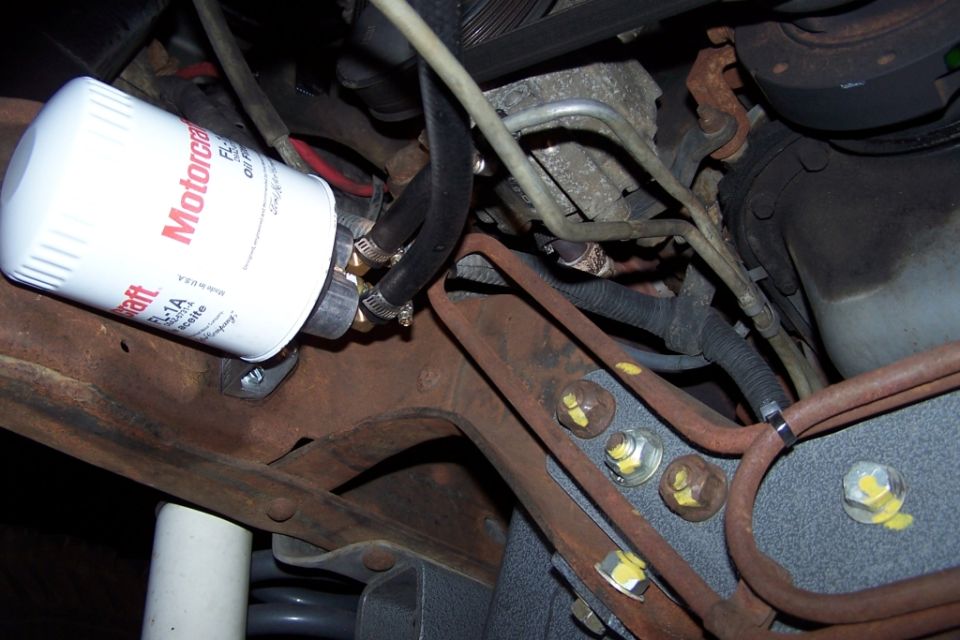 White Motorcraft FL-1A oil filter on a rusty mount with yellow torque-marked bolts