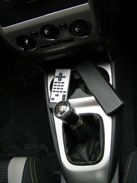 2003 Mazda Protege - Interior view of a car's center console, a manual transmission shifter and electronic accessories.