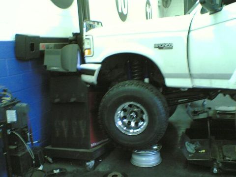 1996 Ford Bronco - A white Ford Bronco is shown on a lift in a garage with its front wheel removed.